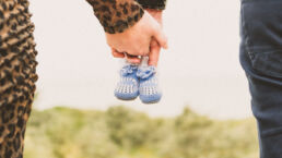 Zwangerschap fotoshoot hand in hand met blauwe babyslofjes