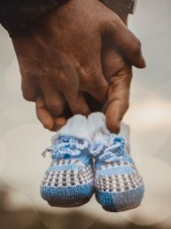 Zwangerschap fotoshoot hand in hand met blauwe babyslofjes