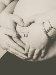 Zwangerschap fotoshoot man en vrouw handen in hartvorm op buik